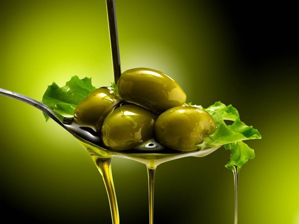 Olives in a spoon covered by oil.