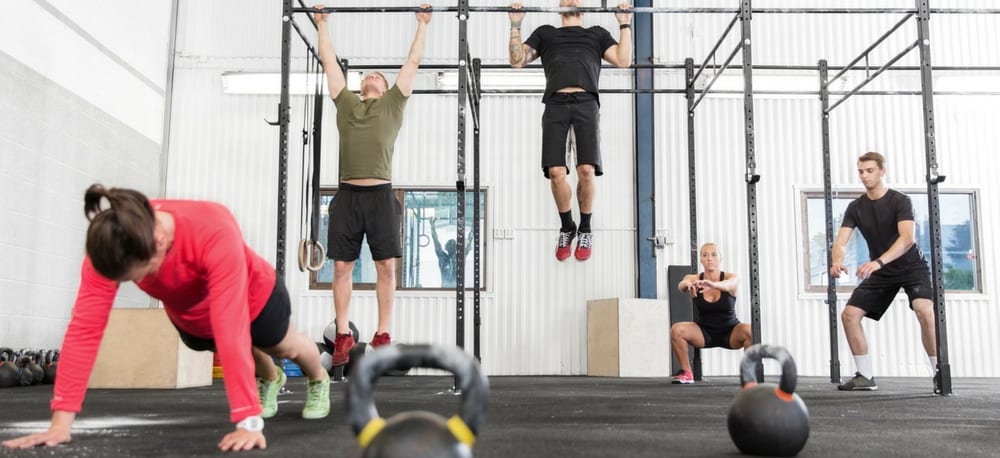 People doing cross fit exercises in a gym.