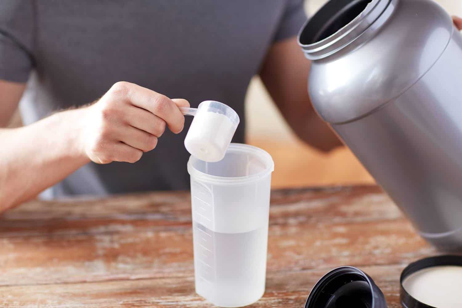 A person making a protein shake by adding powder to water.